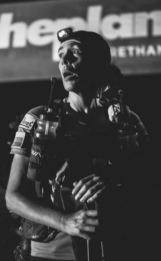 Lisa mid-race at night, headlamp on, focused, exhausted